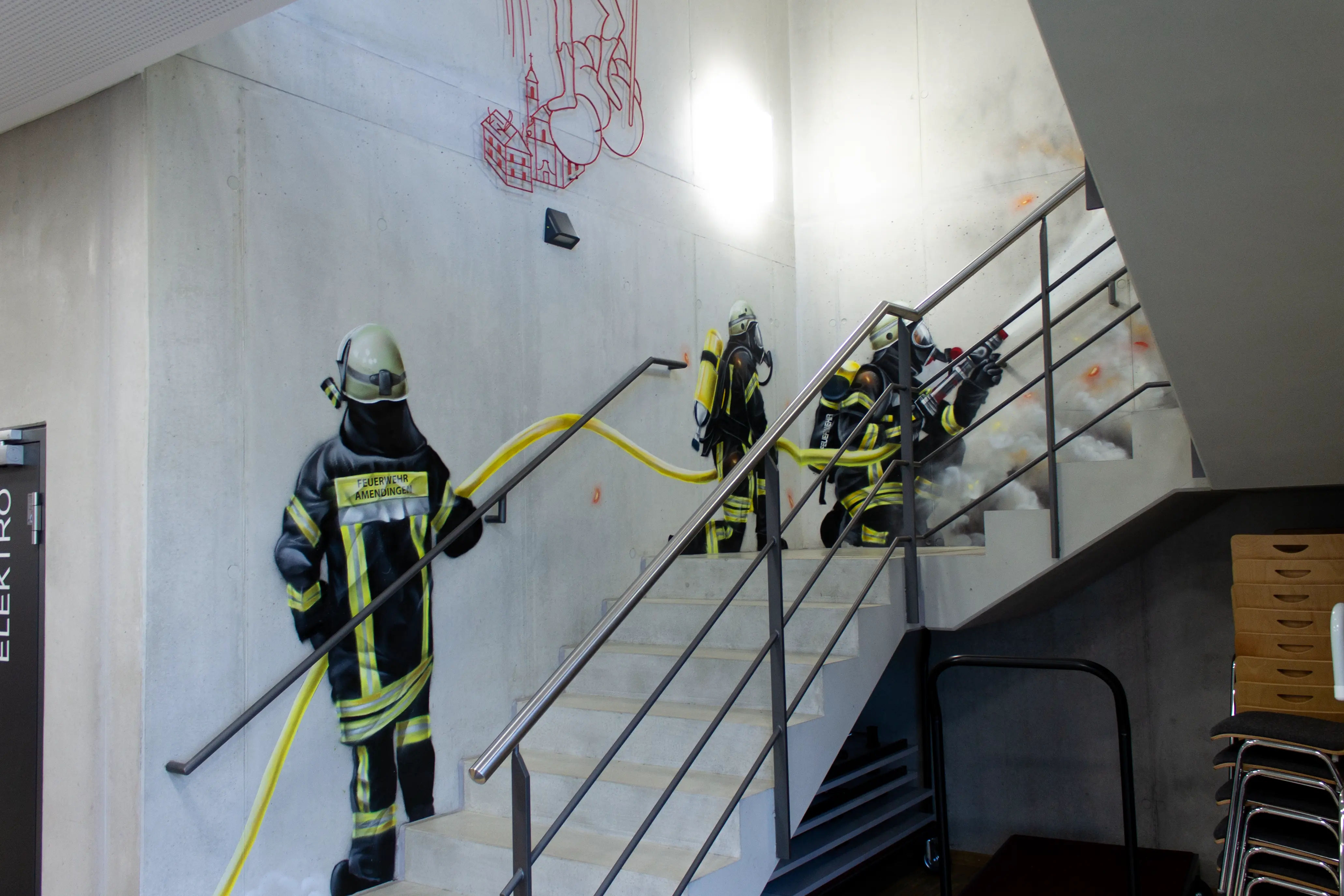 Realistisches Feuerwehr-Graffiti im Treppenhaus mit Einsatzkräften, Löschschlauch und Rauch als Wandgestaltung auf Beton.